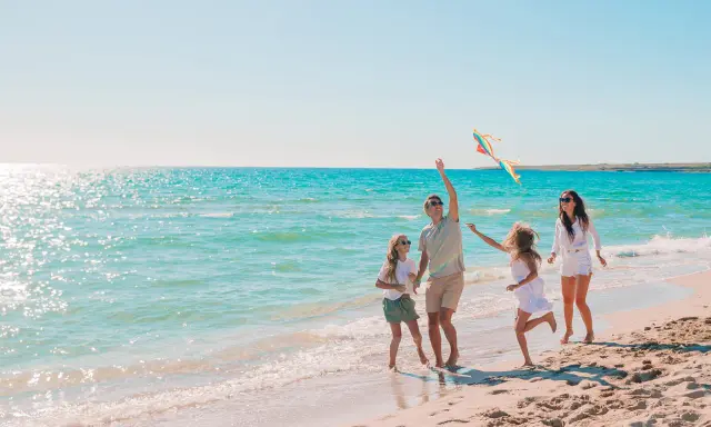 Rodzina puszcza latawiec na plaży. Idealne miejsce, gdzie nad morze z dziećmi tanio i radośnie spędza czas.