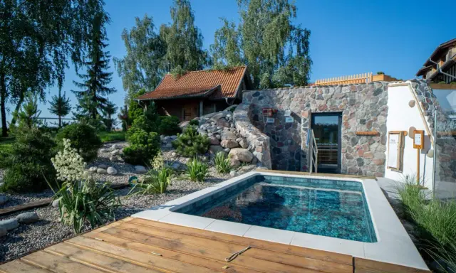 Relaks w polskim spa: basenik, kamienna ściana z wejściem do sauny i urokliwy ogród. Idealne miejsce na odpoczynek.