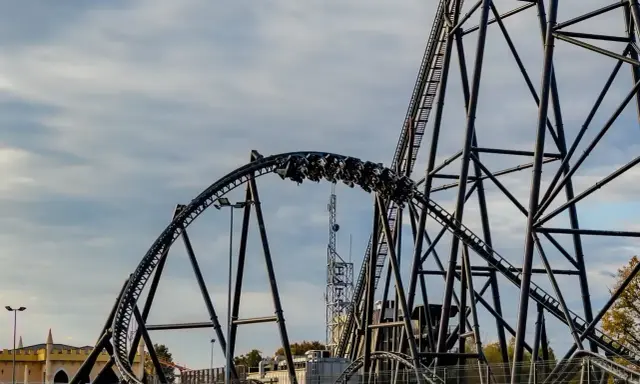Pasażerowie jadą na wagonikach największego rollercoastera w Europie, który pnie się po stalowej konstrukcji.