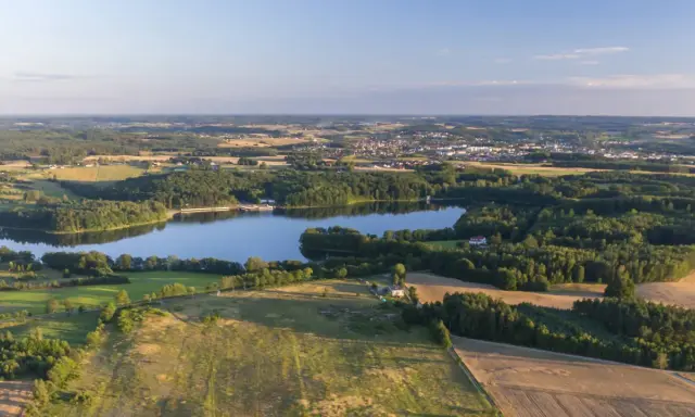 Malownicze jezioro otoczone lasami, z miasteczkiem w tle. Idealne miejsce na rodzinne wycieczki i odkrywanie bytów atrakcji dla dzieci.