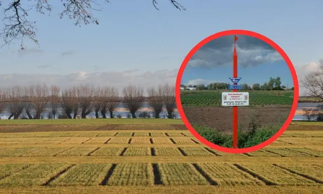 Najniższy punkt w Polsce, oznaczony tablicą informującą o poziomie depresji 1,8 m p.p.m., na tle pola i rzeki.