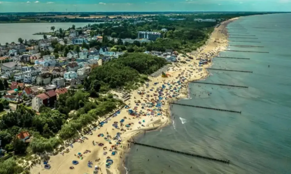 Tłum ludzi na plaży w Mielnie, cieszących się słońcem i morzem. To popularne **Mielno atrakcje** turystyczne.