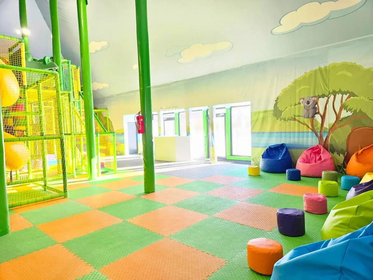 Kolorowy plac zabaw w Sławutówko Park Ewolucji z miękkimi siedziskami i wielopoziomową konstrukcją zachęca do zabawy.