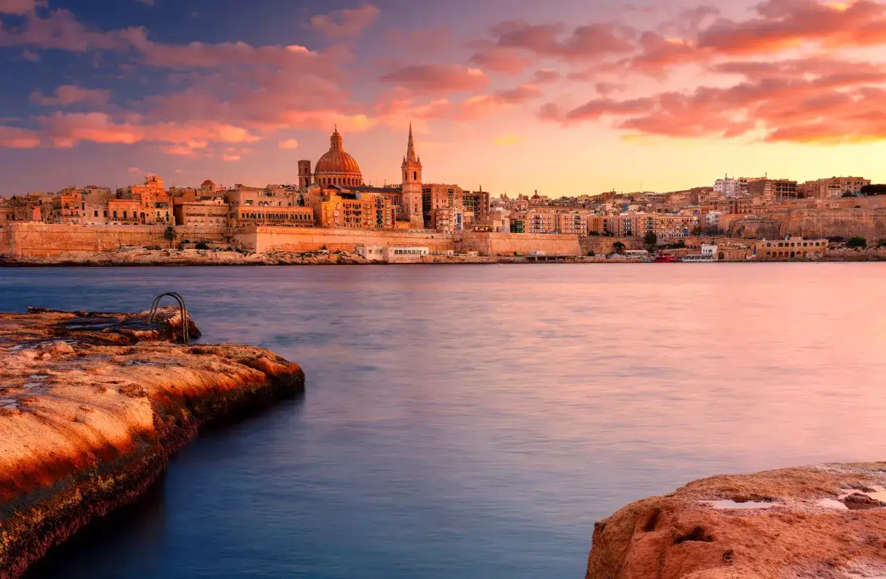 Malta w listopadzie: pogoda zachwyca. Valletta w ciepłych barwach zachodzącego słońca, spokojne morze i skaliste wybrzeże.