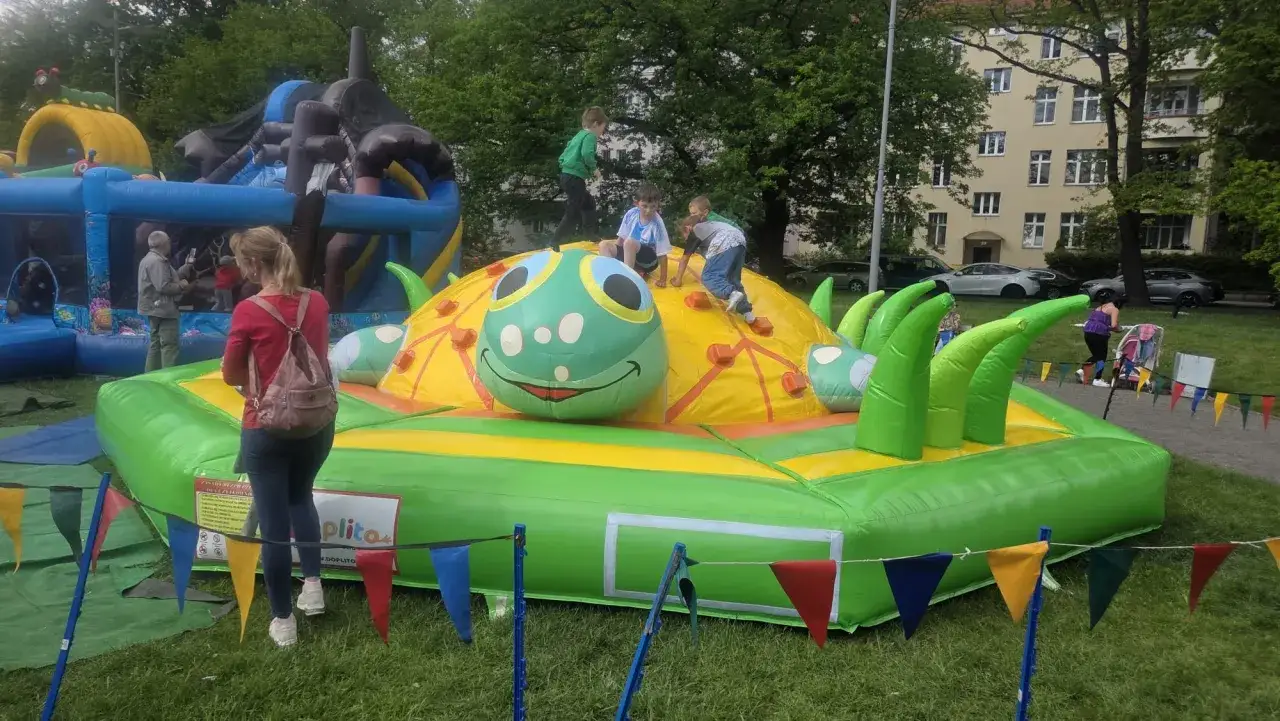 Dzieci bawią się na dmuchanej zjeżdżalni w kształcie gąsienicy, która jest jedną z atrakcji na Dzień Dziecka.