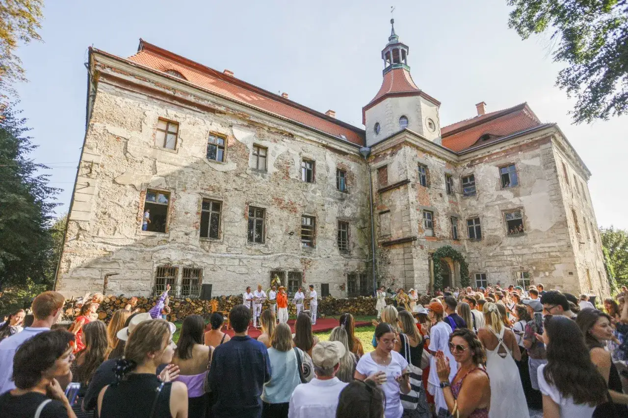 Zamek w Domanicach, zniszczony, ale wciąż majestatyczny, gości tłum ludzi. Na dziedzińcu odbywa się wydarzenie kulturalne.