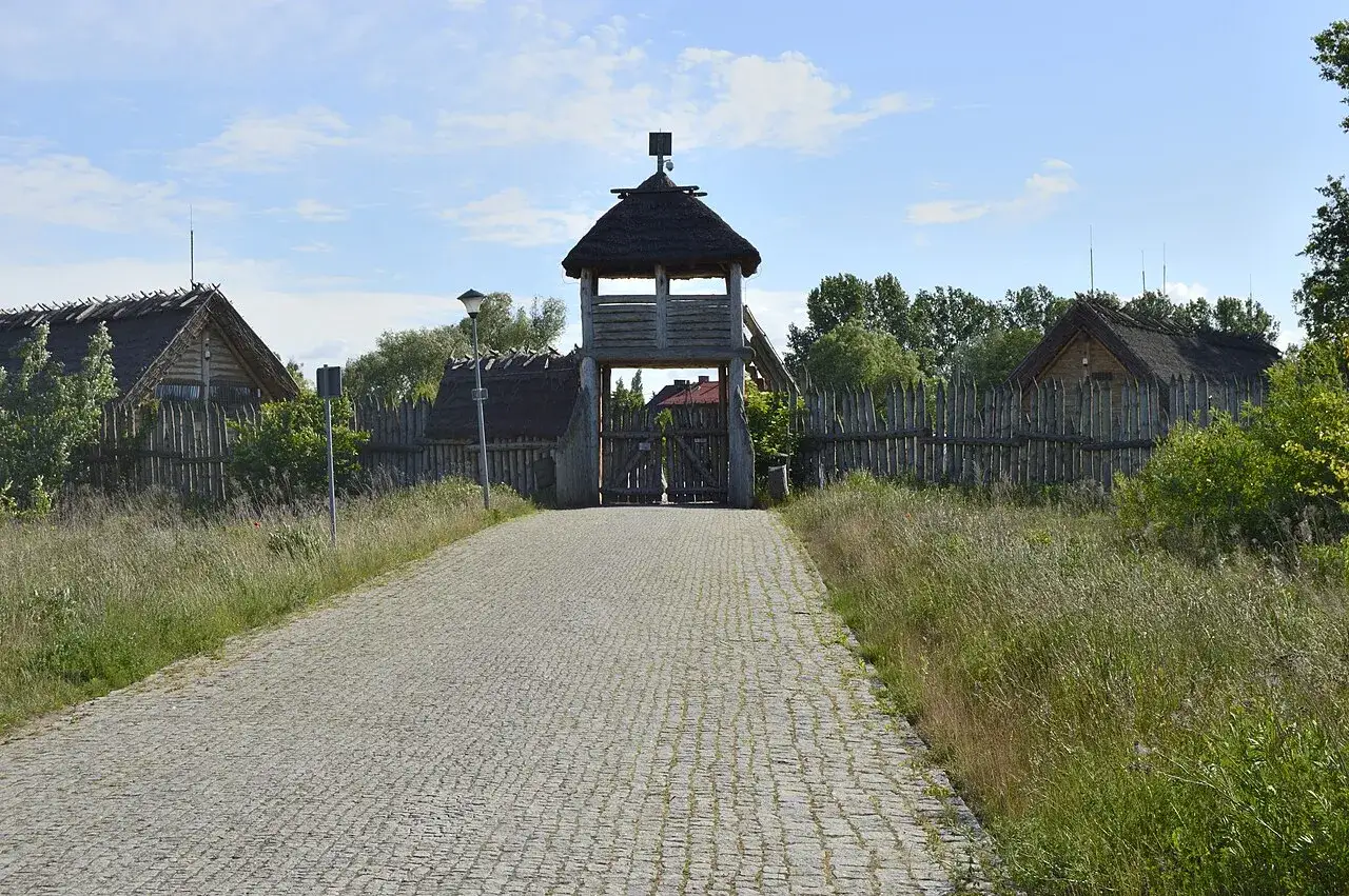 Kamienna droga prowadzi do drewnianej bramy z wieżą. Wokół chaty kryte strzechą i palisada. Pruszcz Gdański atrakcje historyczne.