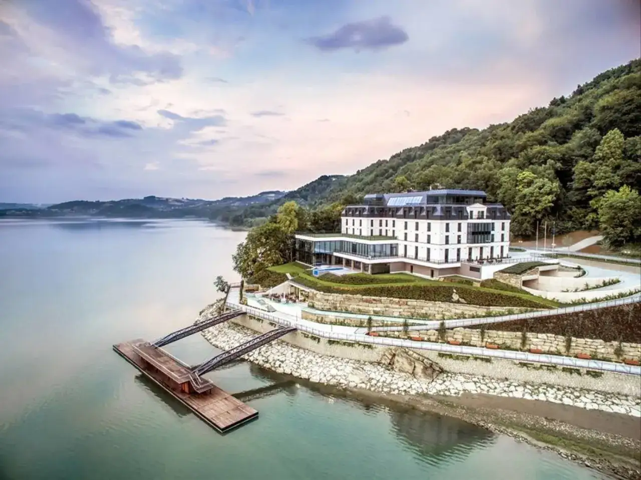 Hotel nad jeziorem, idealny na romantyczne miejsca w Polsce. Widok na spokojną taflę wody i zielone wzgórza.