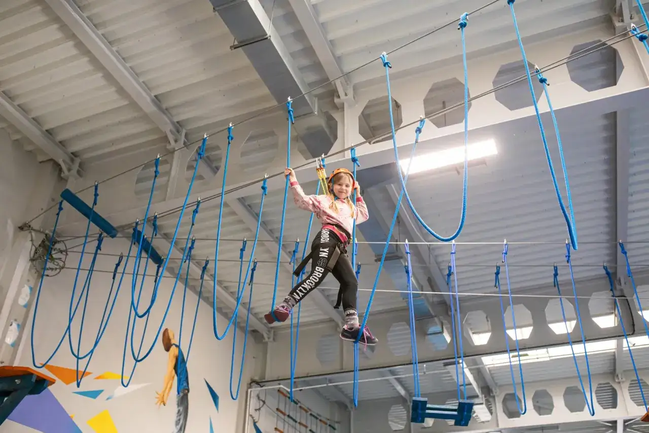 Dziewczynka w kasku pokonuje przeszkody w parku linowym we Wrocławiu. Radość i adrenalina na wysokości!