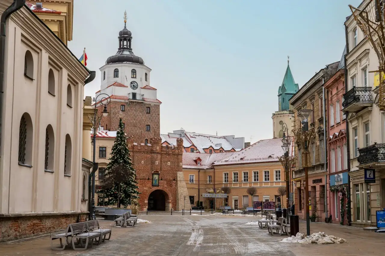 Zimowe wakacje w lutym. Śnieg na dachach, choinka i zabytkowa wieża w centrum miasta.