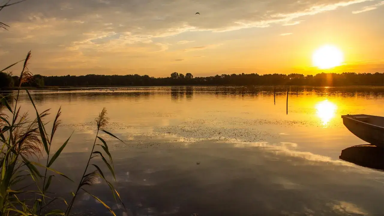Zach&oacute;d słońca nad jeziorem, idealne miejsce, gdzie odpocząć blisko Wrocławia. Ł&oacute;dka czeka na wodzie.