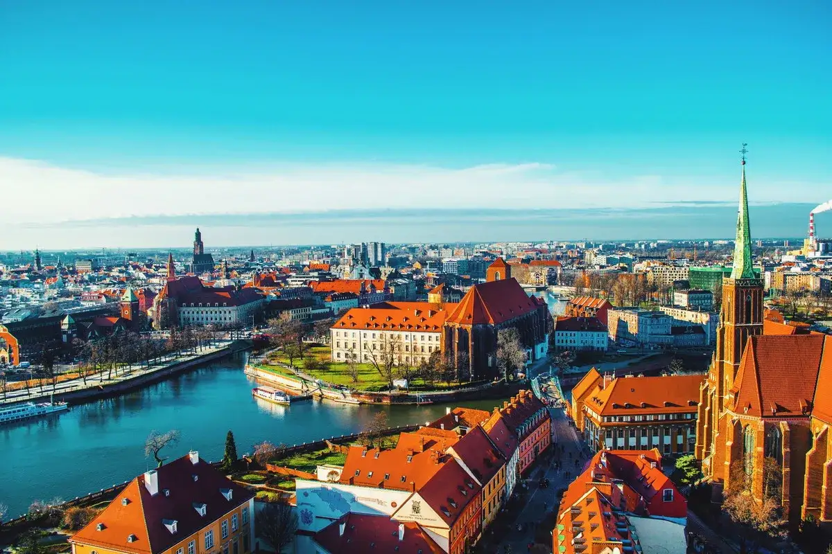 Piękny widok na miasto na weekend. Rzeka, zabytkowe budynki z czerwonymi dachami i zielona wieża kościelna tworzą malowniczy krajobraz.