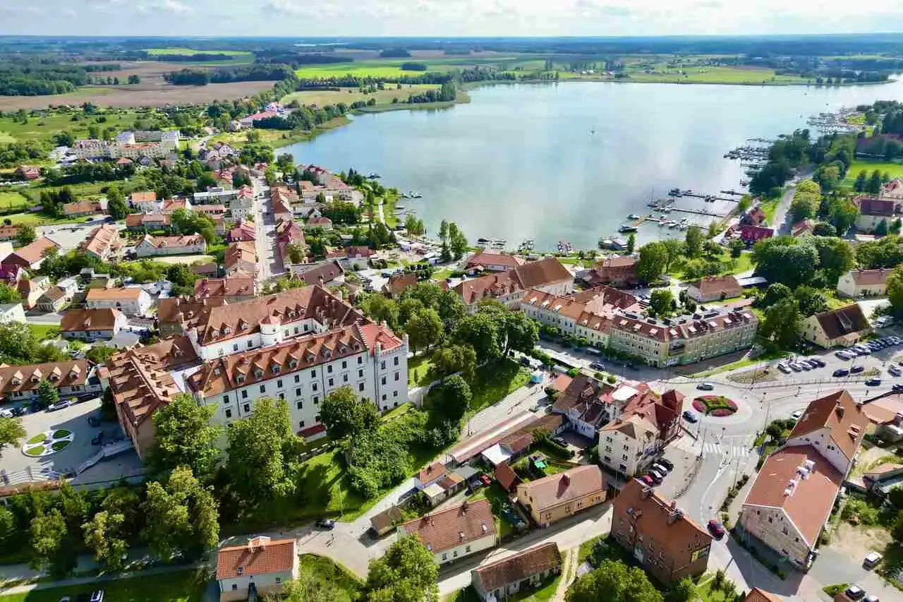 Malownicze zamki na Mazurach w otoczeniu jeziora i zieleni. Widok z lotu ptaka na miasteczko z zabytkową architekturą.