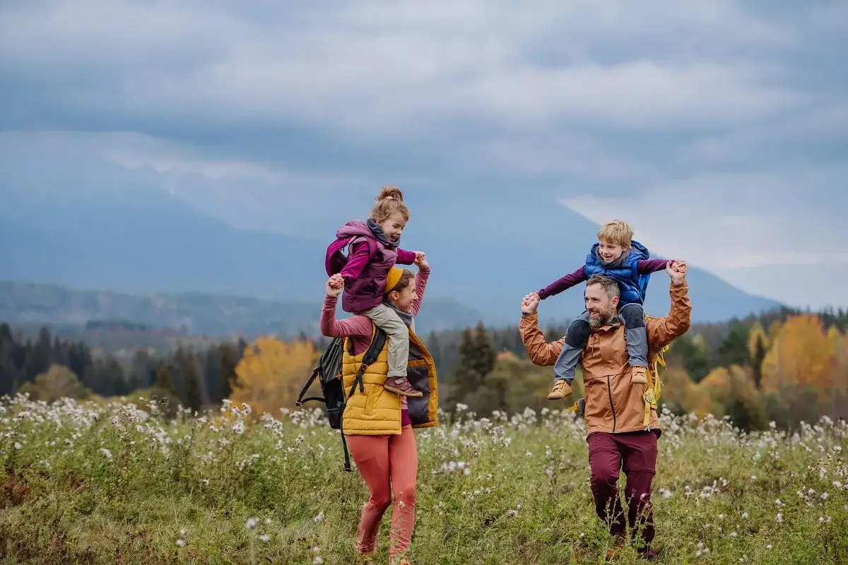 Rodzina na spacerze w górach. Dzieci siedzą na ramionach rodziców. Idealne zakopane szlaki dla dzieci z wózkiem, nawet gdy maluchy chcą być noszone.