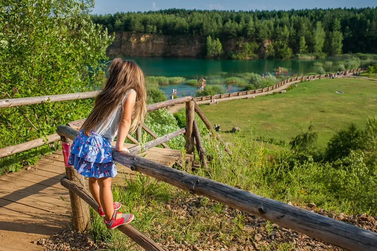 Dziewczynka z długimi włosami podziwia turkusowe jezioro w Jaworznie, które przypomina rajskie Malediwy.