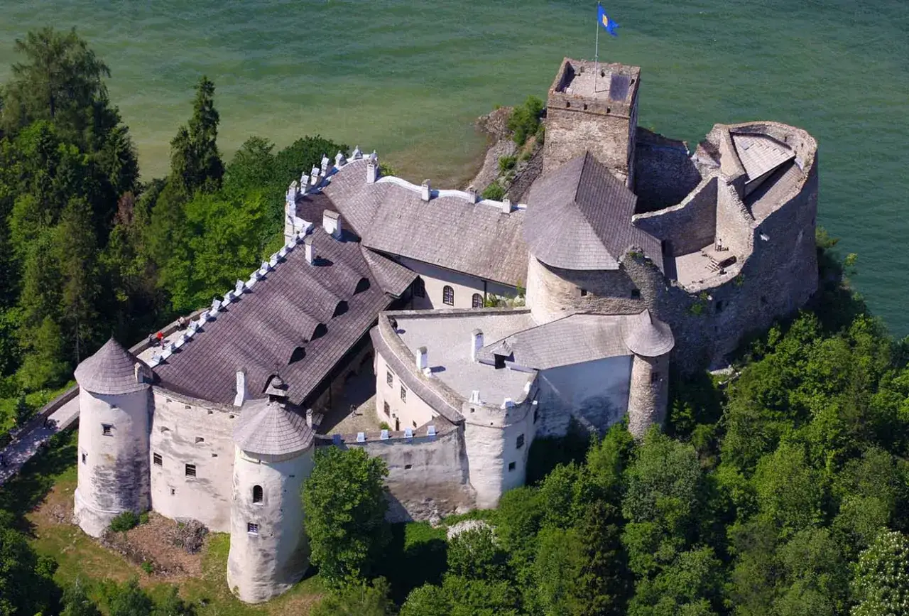 Zamek w Nidzicy, położony nad wodą, otoczony zielenią. Ciekawostki o jego historii i architekturze przyciągają turystów.