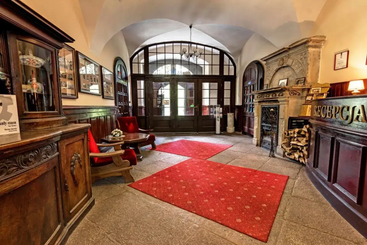 Eleganckie wnętrze z recepcją, kominkiem i wygodnymi fotelami zaprasza na noclegi w zamkach i pałacach.